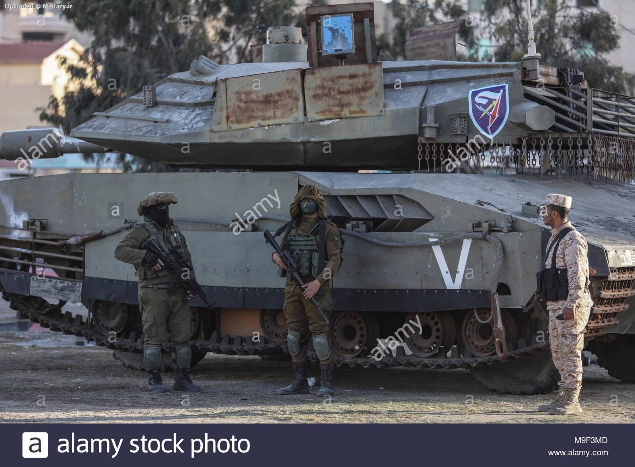 militants-of-izz-ad-din-al-qassam-brigades-the-military-wing-of-the-palestinian-hamas-islamist-movement-stand-guard-next-to-a-life-size-model-of-an-israeli-merkava-tank-during-a-large-scale-dri.jpg